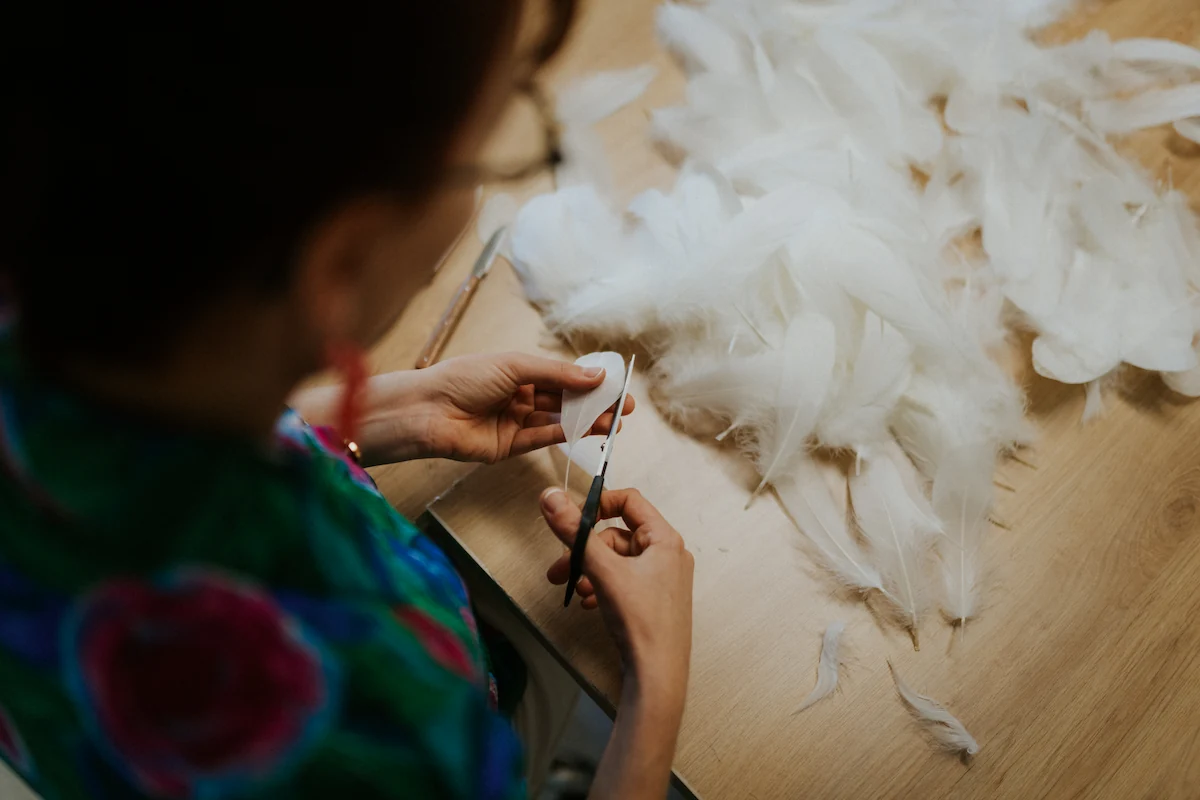 Amandine, plumassière, découpe ses plumes d'oie délicatement.
